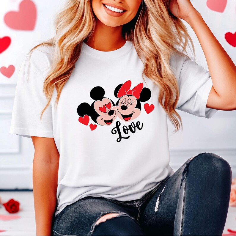 May include: White t-shirt with a graphic of Mickey Mouse and Minnie Mouse kissing with red hearts and the word "Love" printed below.