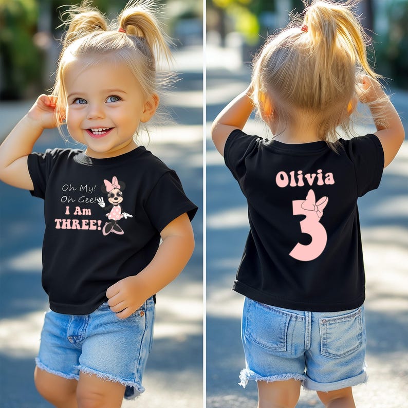 May include: Black t-shirt with the text "Oh My! Oh Gee! I Am THREE!" and a Minnie Mouse graphic. The back of the shirt has the name "Olivia" and the number "3" with a bow. The child is wearing blue denim shorts.