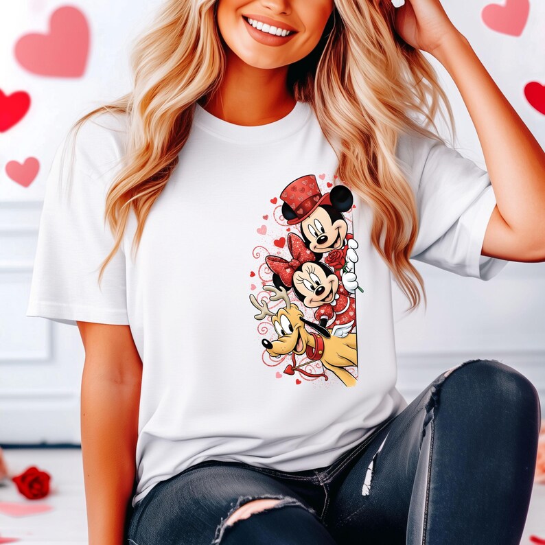 Puede incluir: Camiseta blanca con un gr&aacute;fico colorido de Mickey Mouse, Minnie Mouse y Pluto con atuendos de San Valent&iacute;n. Mickey lleva un sombrero de copa, Minnie un lazo y Pluto tiene cuernos. El dise&ntilde;o incluye corazones y una rosa.