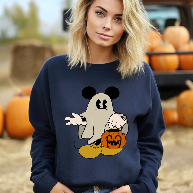 Pode incluir: Camisola azul marinho com Mickey Mouse fantasiado de fantasma segurando uma ab&oacute;bora. O design inclui orelhas pretas, uma fantasia de fantasma branca e uma lanterna de ab&oacute;bora laranja. Um item com tema de outono.