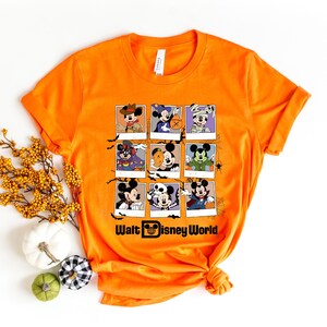 Op de afbeelding: Oranje T-shirt met een afbeelding van Mickey Mouse en zijn vrienden verkleed in Halloween-kostuums. De afbeelding is in een raster van negen vierkanten gerangschikt. De tekst "Walt Disney World" staat onderaan de afbeelding.