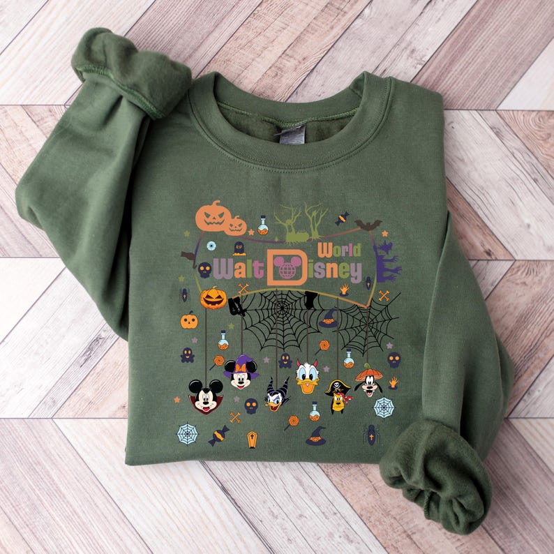 May include: Green sweatshirt with a Halloween-themed design featuring Mickey Mouse and other Disney characters. The design includes a banner that says "Walt Disney World" and various Halloween icons like pumpkins, bats, and spiderwebs.