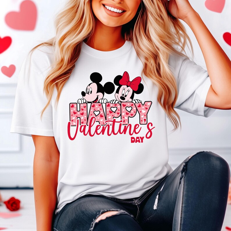 May include: White t-shirt with a pink and red heart pattern. Mickey Mouse and Minnie Mouse are peeking over the text "Happy Valentine's Day".