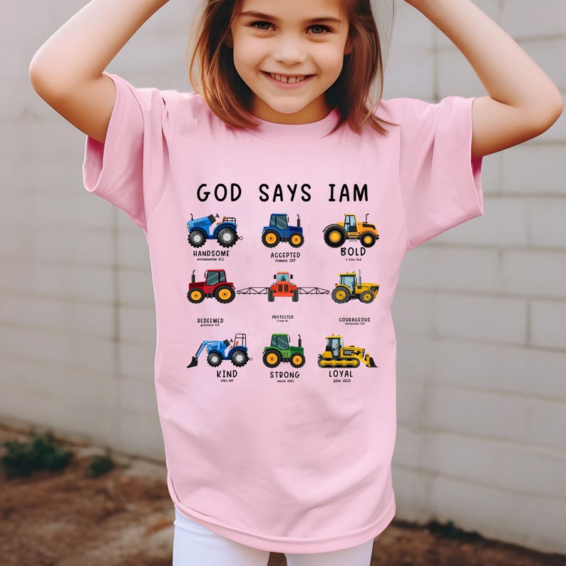 May include: Pink t-shirt with the text "God Says I Am" and a graphic of tractors with words like "handsome", "accepted", "bold", "redeemed", "protected", "courageous", "kind", "strong", and "loyal".