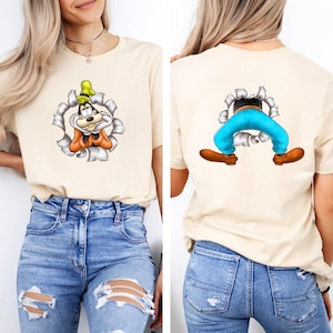 K&ouml;nnte beinhalten: Beiges T-Shirt mit einer Cartoonfigur, mit einem zerrissenen Papiereffekt. Die Vorderseite zeigt das Gesicht der Figur, w&auml;hrend die R&uuml;ckseite die Beine und F&uuml;&szlig;e der Figur zeigt. Die Figur tr&auml;gt einen gr&uuml;nen Hut, eine orangefarbene Weste und eine blaue Hose.