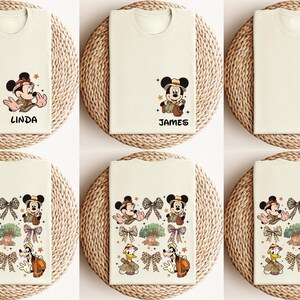 May include: Six white t-shirts with different Disney character designs. The designs include Mickey Mouse, Donald Duck, and Goofy. The shirts are all in a safari theme and have the names Linda, James, and Paul printed on them.