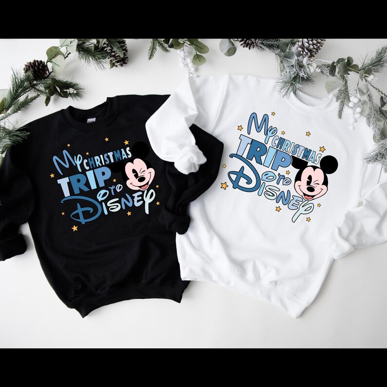 Puede incluir: Dos sudaderas negras y blancas con un dise&ntilde;o gr&aacute;fico azul y blanco. El gr&aacute;fico presenta a Mickey Mouse y el texto "My Christmas Trip to Disney".