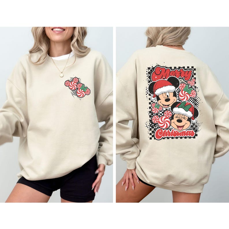 May include: A beige sweatshirt featuring a Christmas-themed design. The front has a small candy cane Mickey Mouse design. The back displays Mickey and Minnie Mouse wearing Santa hats, surrounded by candy canes, with the words "Merry Christmas".