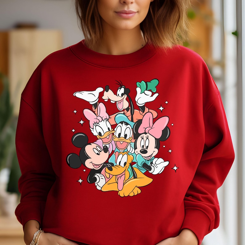 May include: Red sweatshirt with a graphic print of Mickey Mouse, Minnie Mouse, Donald Duck, Goofy, and Pluto. The characters are all smiling and appear to be hugging each other.