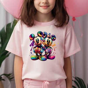 May include: A pink t-shirt with a colorful graphic of Mickey Mouse and Minnie Mouse holding hands. The graphic is surrounded by colorful paint splatters.