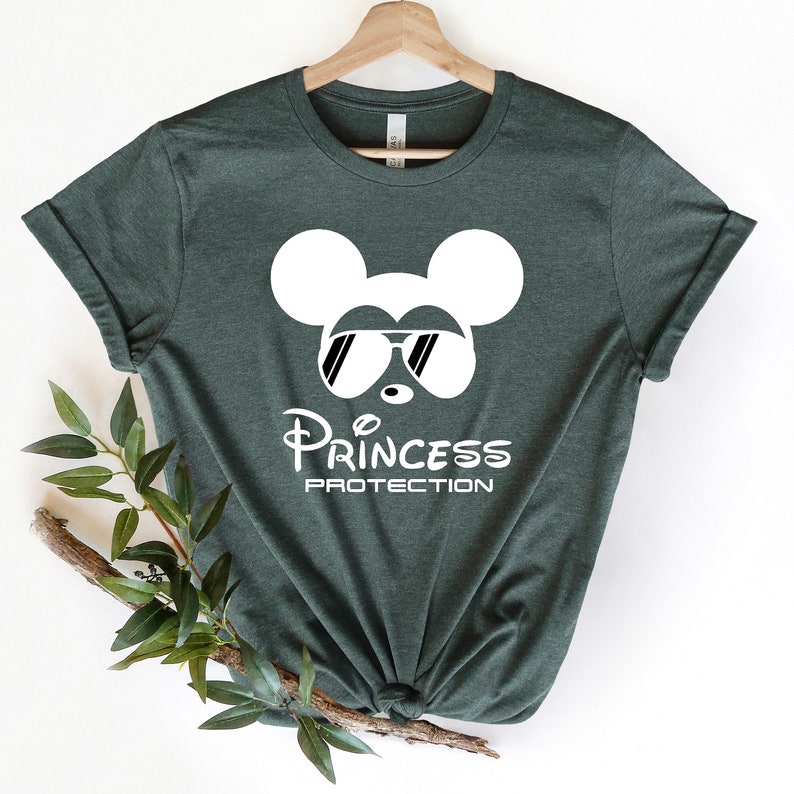 May include: A dark green t-shirt with a white Mickey Mouse silhouette wearing sunglasses and the text "Princess Protection".