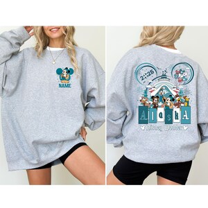 May include: Gray sweatshirt with a Mickey Mouse design on the front and a Disney Wonder cruise ship design on the back. The back design includes the text "Alaska" and "Disney Wonder".