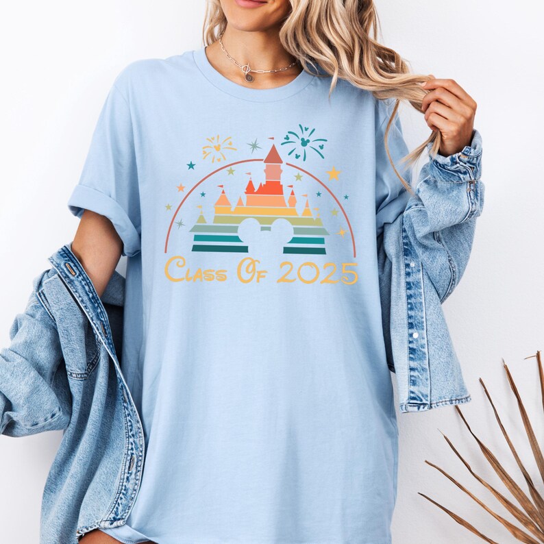 May include: Light blue t-shirt with a rainbow-colored graphic of the Disney castle and fireworks. The text "Class of 2025" is printed below the graphic.