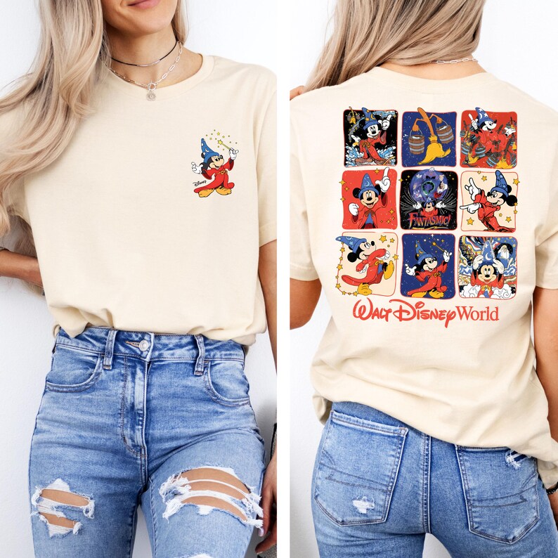 Puede incluir: Una camiseta de color crema con una ilustraci&oacute;n de Mickey Mouse en la parte delantera y una ilustraci&oacute;n de Mickey Mouse de varios paneles en la parte trasera. La ilustraci&oacute;n de la parte trasera presenta a Mickey Mouse en diferentes poses como mago. El texto "Walt Disney World" est&aacute; impreso debajo de la ilustraci&oacute;n. La modelo lleva pantalones vaqueros azules.