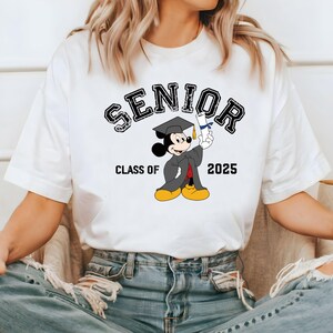 K&ouml;nnte beinhalten: Wei&szlig;es T-Shirt mit einer schwarzen Grafik von Mickey Mouse, der einen Abschluss-Hut tr&auml;gt und ein Diplom h&auml;lt. Der Text "SENIOR" befindet sich &uuml;ber Mickey Mouse und "CLASS OF 2025" darunter.