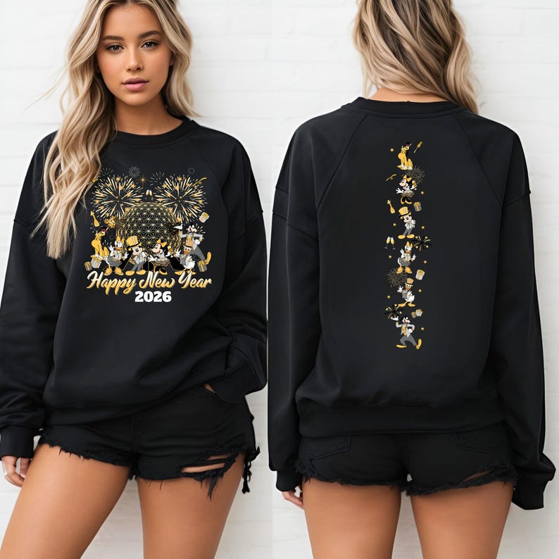 May include: Black sweatshirt with a gold and white graphic featuring fireworks, cartoon characters, and the text "Happy New Year 2026." The back of the sweatshirt has a vertical design of cartoon characters. The model is wearing black shorts.