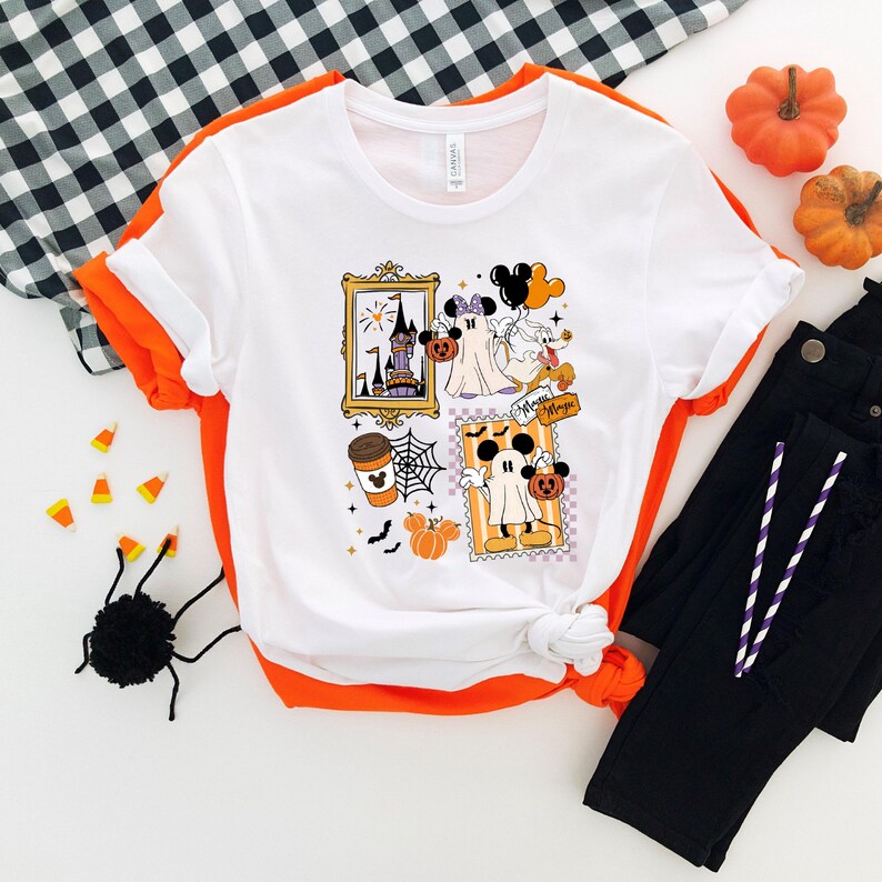Puede incluir: Camiseta blanca con ribete naranja con gr&aacute;ficos tem&aacute;ticos de Halloween. El dise&ntilde;o incluye im&aacute;genes enmarcadas de un castillo, Mickey Mouse como fantasma, una taza de caf&eacute;, una telara&ntilde;a, calabazas y el texto "Minnie Magic".