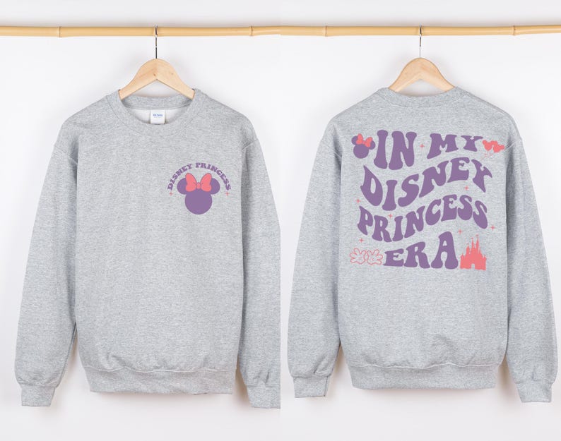 Puede incluir: Sudadera gris con un gr&aacute;fico de Disney Princess morado y rosa en la parte delantera y el texto "In My Disney Princess Era" en la parte posterior.