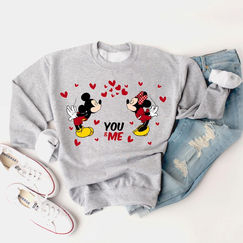 May include: Gray sweatshirt with a graphic of Mickey Mouse and Minnie Mouse kissing. The graphic is surrounded by red hearts and the text "YOU & ME".