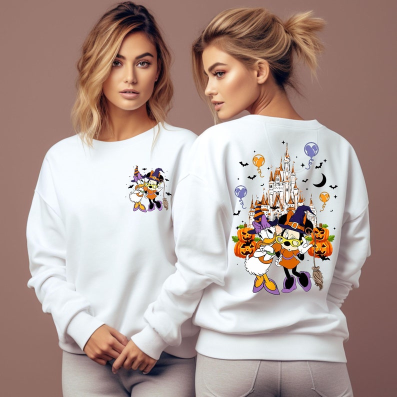 May include: White sweatshirt featuring a Halloween-themed graphic of cartoon characters. The front has a small image, while the back displays a larger design with a castle, pumpkins, and balloons. The characters are dressed in Halloween costumes.