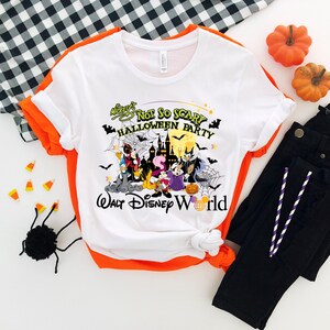 May include: White t-shirt with a graphic of Mickey Mouse and friends in a Halloween party setting. The text reads "Mickey's Not So Scary Halloween Party Walt Disney World".