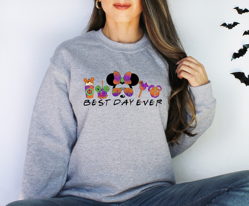 May include: Gray sweatshirt with a Halloween-themed graphic featuring Mickey Mouse, Minnie Mouse, and other Disney characters. The text "BEST DAY EVER" is printed below the graphic.