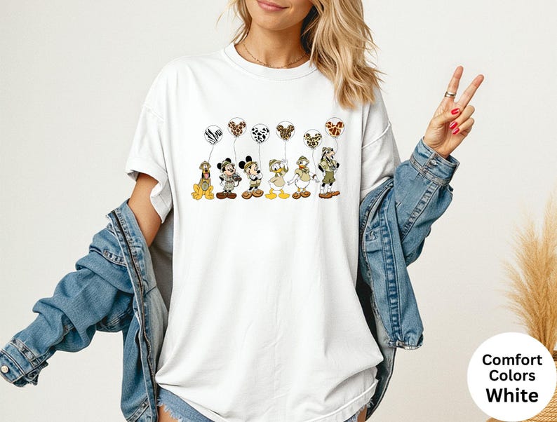 K&ouml;nnte beinhalten: Wei&szlig;es T-Shirt mit Zeichentrickfiguren, die Luftballons mit Tiermotiven halten. Die Figuren sind Pluto, Micky Maus, Minnie Maus, Donald Duck und Goofy. Das Shirt hat die Worte "Comfort Colors White" unten rechts.
