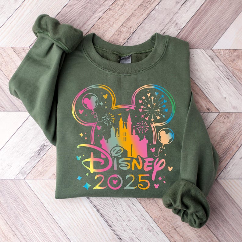 May include: A green sweatshirt with a rainbow-colored Mickey Mouse silhouette and the text "DISNEY 2025" on the front.
