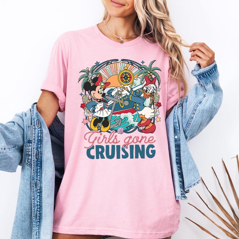 May include: Pink t-shirt with a graphic of Mickey Mouse and Daisy Duck dressed as sailors on a boat. The text "Girls gone cruising" is printed below the graphic.