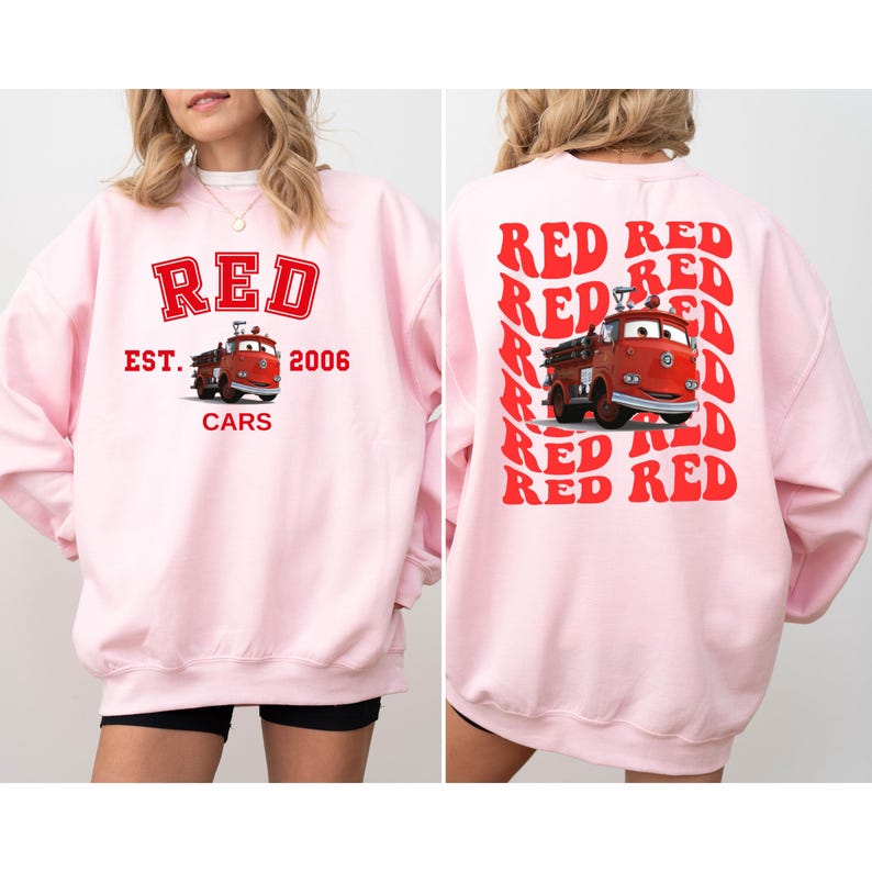 May include: Pink sweatshirt with a red graphic of a fire truck and the text "RED EST. 2006 CARS" on the front. The back of the sweatshirt has the word "RED" repeated in a diagonal pattern.