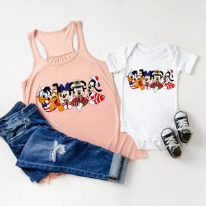 Peut inclure: Un d&eacute;bardeur rose et un body blanc avec un motif de Mickey Mouse, Donald Duck, Dingo, Pluto et Minnie Mouse habill&eacute;s en marins. Le motif est en ligne et les personnages sourient tous.