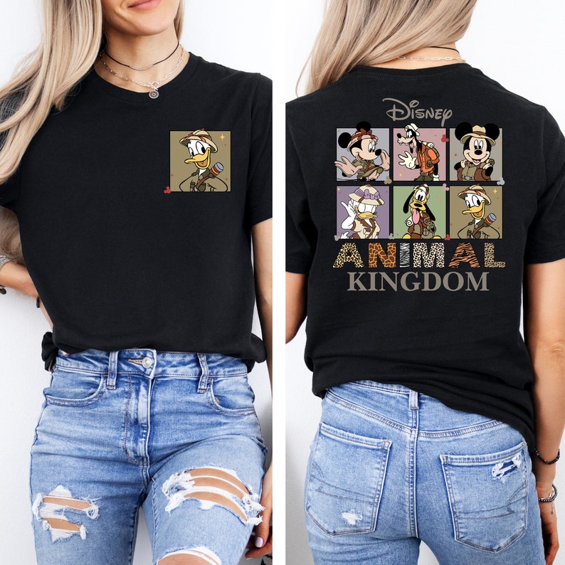 Pu&ograve; includere: Maglietta nera con una grafica di personaggi Disney vestiti con abiti da safari. Il testo "Disney Animal Kingdom" &egrave; stampato sotto la grafica.