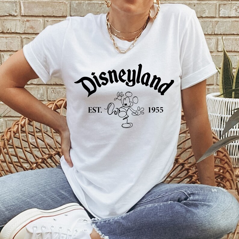 May include: White t-shirt with a black graphic of Mickey Mouse and the text "Disneyland Est. 1955".