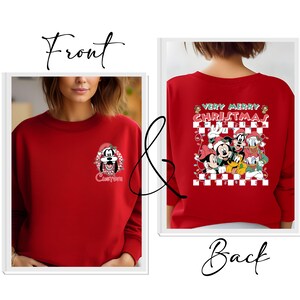 May include: Red sweatshirt featuring a cartoon of Goofy wearing a Santa hat with the word "Custom" below. The back of the sweatshirt displays Mickey, Minnie, Donald, and Goofy with the text "Very Merry Christmas" on a checkered background.