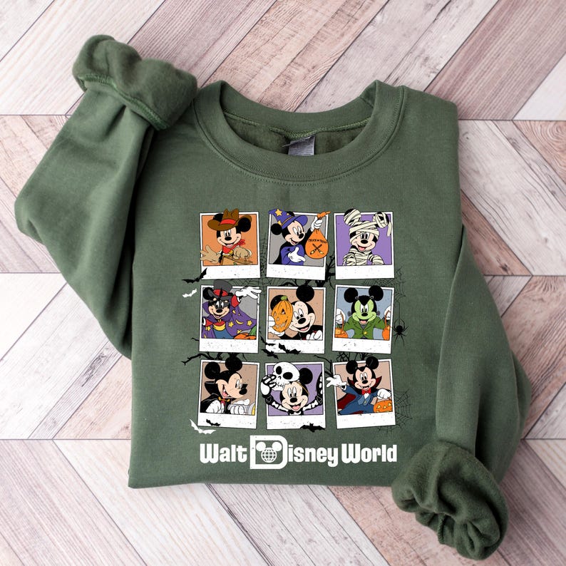 Op de afbeelding: Groen sweatshirt met een afbeelding van Mickey Mouse in verschillende Halloween-kostuums. De afbeelding is gerangschikt in een raster van negen vierkanten. De tekst "Walt Disney World" staat onderaan de afbeelding.