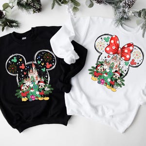 Puede incluir: Dos sudaderas con tem&aacute;tica navide&ntilde;a en blanco y negro con una silueta de Mickey Mouse y un lazo rojo. Las sudaderas presentan una imagen de dibujos animados de Mickey Mouse y Minnie Mouse con un &aacute;rbol de Navidad y el castillo de Cenicienta.