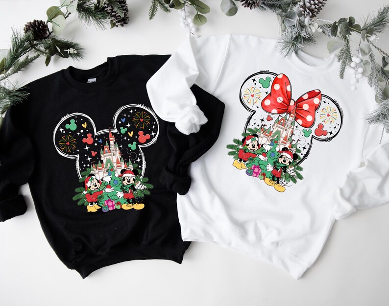 Puede incluir: Dos sudaderas con tem&aacute;tica navide&ntilde;a en blanco y negro con una silueta de Mickey Mouse y un lazo rojo. Las sudaderas presentan una imagen de dibujos animados de Mickey Mouse y Minnie Mouse con un &aacute;rbol de Navidad y el castillo de Cenicienta.