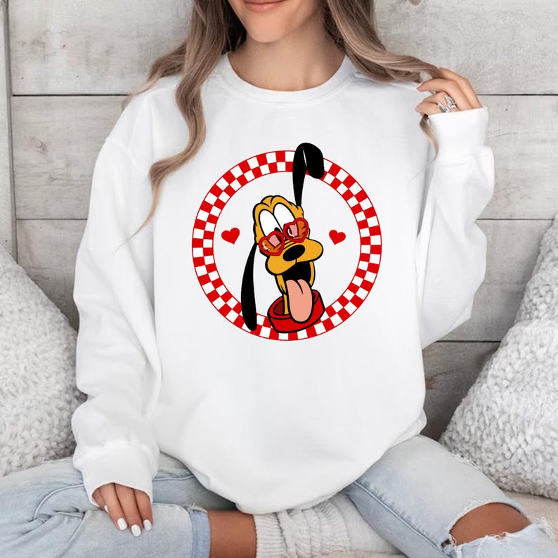 May include: White sweatshirt with a red and white checkered circle design featuring a cartoon dog wearing heart-shaped sunglasses. The dog is sticking its tongue out.
