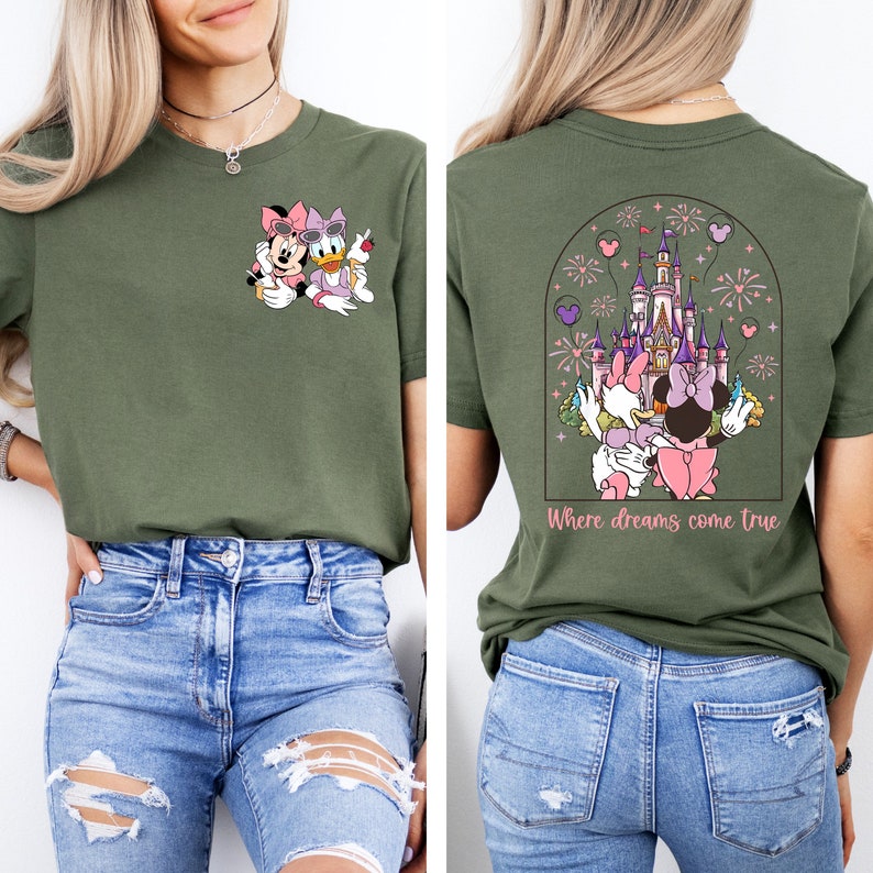 Pu&ograve; includere: Una maglietta verde con un'immagine di cartone animato di Minnie Mouse e Daisy Duck sul davanti. La parte posteriore della maglietta ha un'immagine di cartone animato di Minnie Mouse e Daisy Duck di fronte a un castello rosa con il testo "Where dreams come true".
