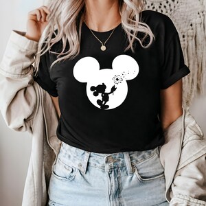 May include: Black t-shirt with a white silhouette of Mickey Mouse blowing on a dandelion.