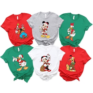 May include: A collection of six short-sleeved t-shirts in various colors, each featuring a different Disney character in a Christmas theme. Characters include Mickey Mouse, Donald Duck, Goofy, Pluto, and Daisy Duck, all adorned with festive decorations.