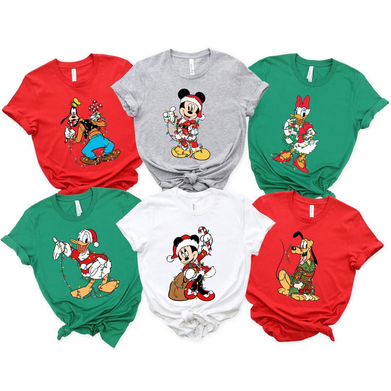 May include: A collection of six short-sleeved t-shirts in various colors, each featuring a different Disney character in a Christmas theme. Characters include Mickey Mouse, Donald Duck, Goofy, Pluto, and Daisy Duck, all adorned with festive decorations.