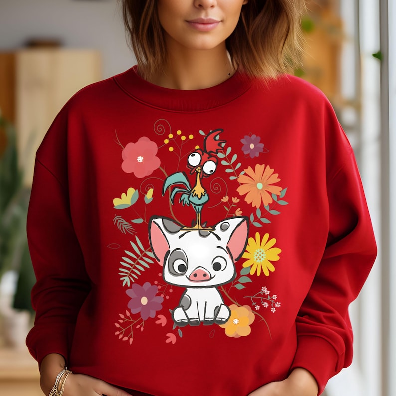 Puede incluir: Sudadera roja con un dise&ntilde;o de dibujos animados de un gallo y un cerdo. El gallo est&aacute; encaramado en la cabeza del cerdo. El dise&ntilde;o est&aacute; rodeado de flores coloridas.