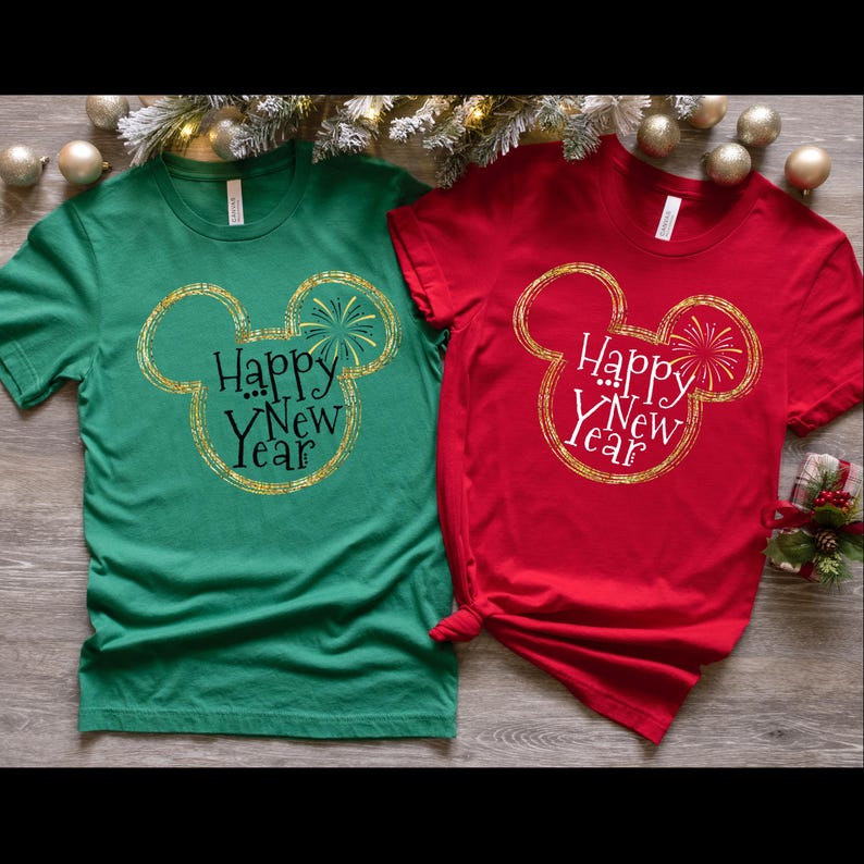 May include: Two t-shirts with a gold Mickey Mouse head design and the text "Happy New Year". One shirt is green and the other is red.