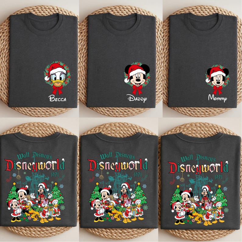 Op de afbeelding: Donkergrijze t-shirts met kerstthema Disney-personageontwerpen. E&eacute;n shirt toont Donald Duck met "Becca", een ander Mickey Mouse met "Daddy", en een derde met "Mommy". De andere shirts hebben een Disney World 1971 ontwerp.