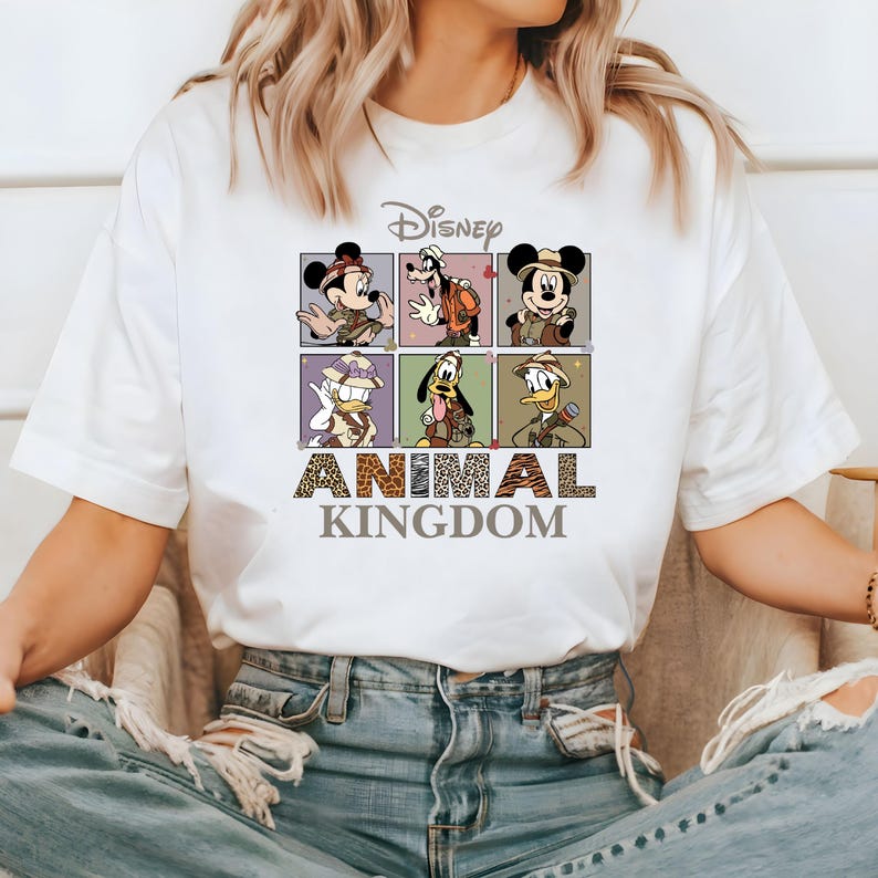 May include: White t-shirt with a graphic of Disney characters in safari outfits. The text "Disney Animal Kingdom" is printed below the characters.