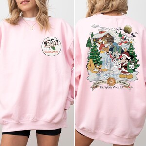 May include: Pink sweatshirt with a Mickey Mouse and Minnie Mouse graphic on the front and a Christmas scene with Mickey Mouse and friends on the back. The back graphic includes the text "Main Street Plaza In The Shadows Our Disney World".