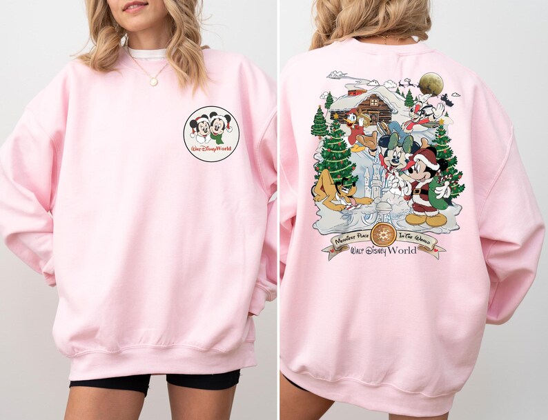 May include: Pink sweatshirt with a Mickey Mouse and Minnie Mouse graphic on the front and a Christmas scene with Mickey Mouse and friends on the back. The back graphic includes the text "Main Street Plaza In The Shadows Our Disney World".