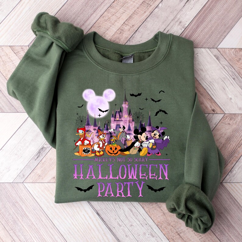 Puede incluir: Sudadera verde con un gr&aacute;fico morado y blanco de Mickey Mouse y sus amigos vestidos con disfraces de Halloween frente a un castillo. El texto "Mickey's Not So Scary Halloween Party" est&aacute; impreso debajo del gr&aacute;fico.