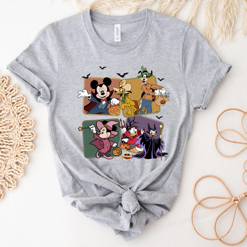 Puede incluir: Camiseta gris claro con un dise&ntilde;o tem&aacute;tico de Halloween. El dise&ntilde;o presenta personajes de dibujos animados disfrazados, como Mickey Mouse como vampiro y Minnie Mouse como bruja. El dise&ntilde;o tambi&eacute;n incluye murci&eacute;lagos.